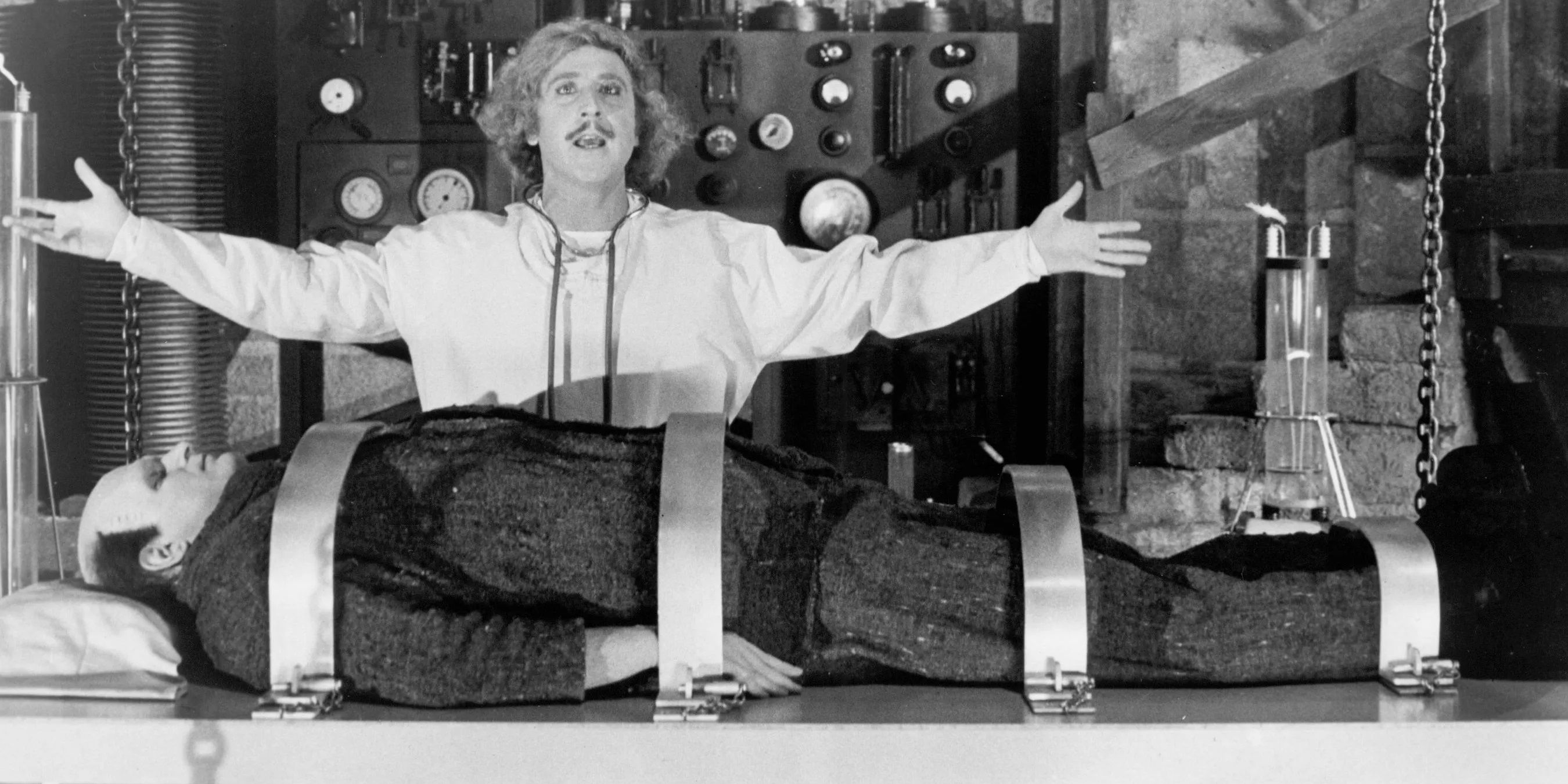 Frederick Frankenstein with his arms open with the monster on his operating table in Young Frankenstein