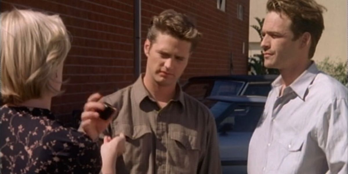 Kelly holding out her hand, Brandon taking a ring box back and Dylan standing alongside them in Beverly Hills 90210