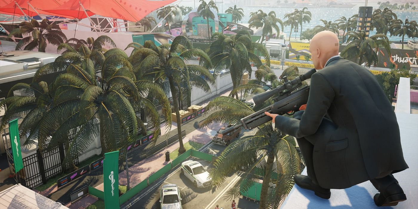 Agent 47 kneels on a rooftop with a sniper rifle in Hitman 2