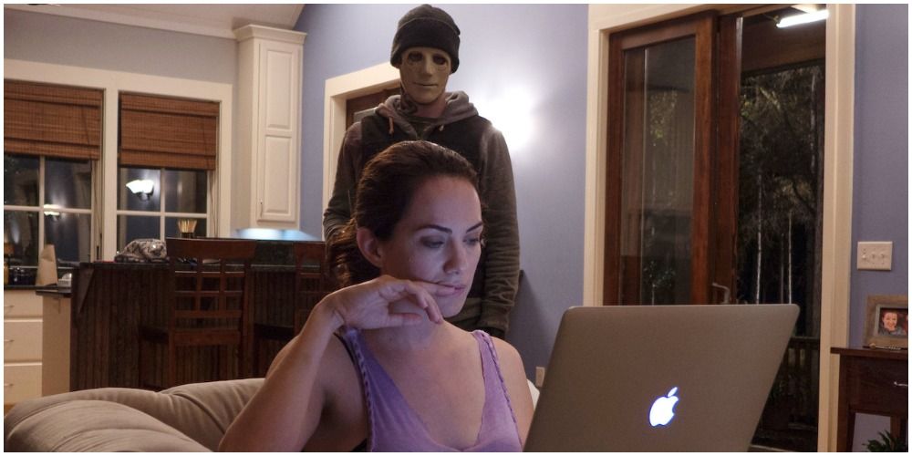 Masked Person Standing Behind Woman On Computer
