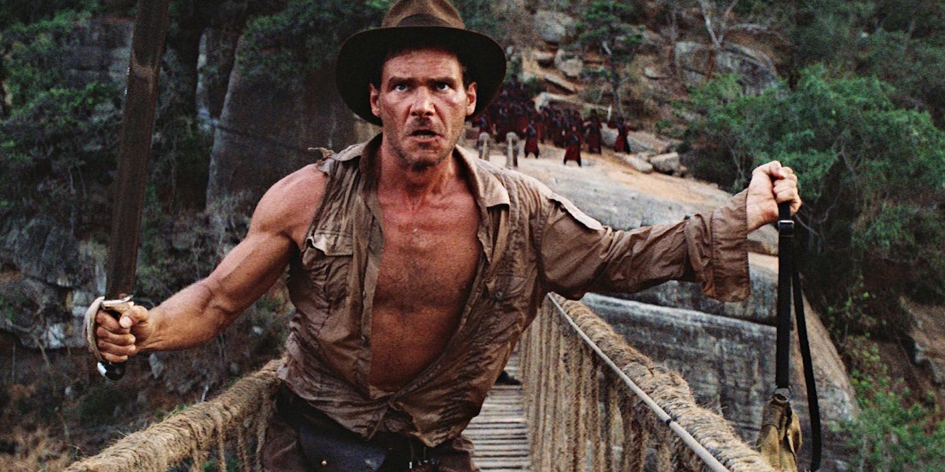 Indiana Jones holds a bag and a sword in Indiana Jones and the Temple of Doom