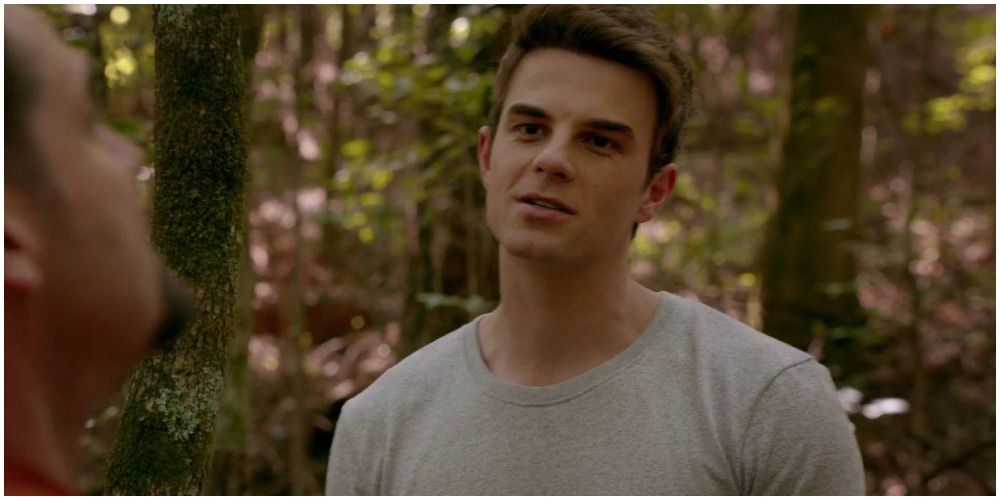 Kol Mikaelson in a grey tee, talking outdoors to someone in The Vampire Diaries