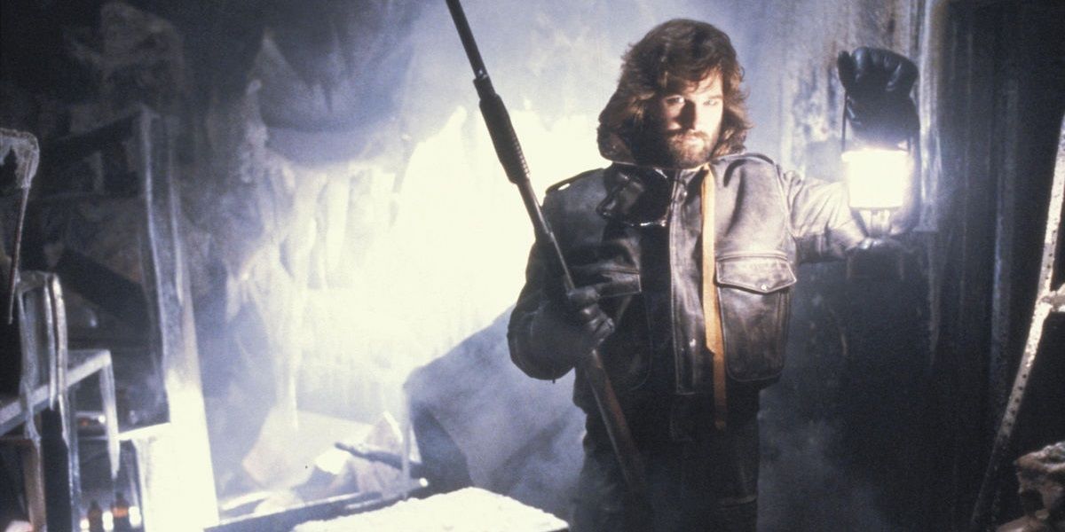 Kurt Russell holding a lantern and a shotgun in The Thing