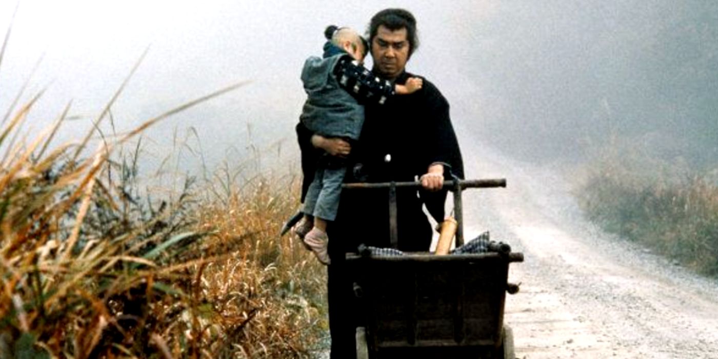 Tomisaburo Wakayama como Ogami Ittō carregando Akihiro Tomikawa como Ogami Daigoro na estrada em Lone Wolf and Cub: Sword of Vengeance (1972)