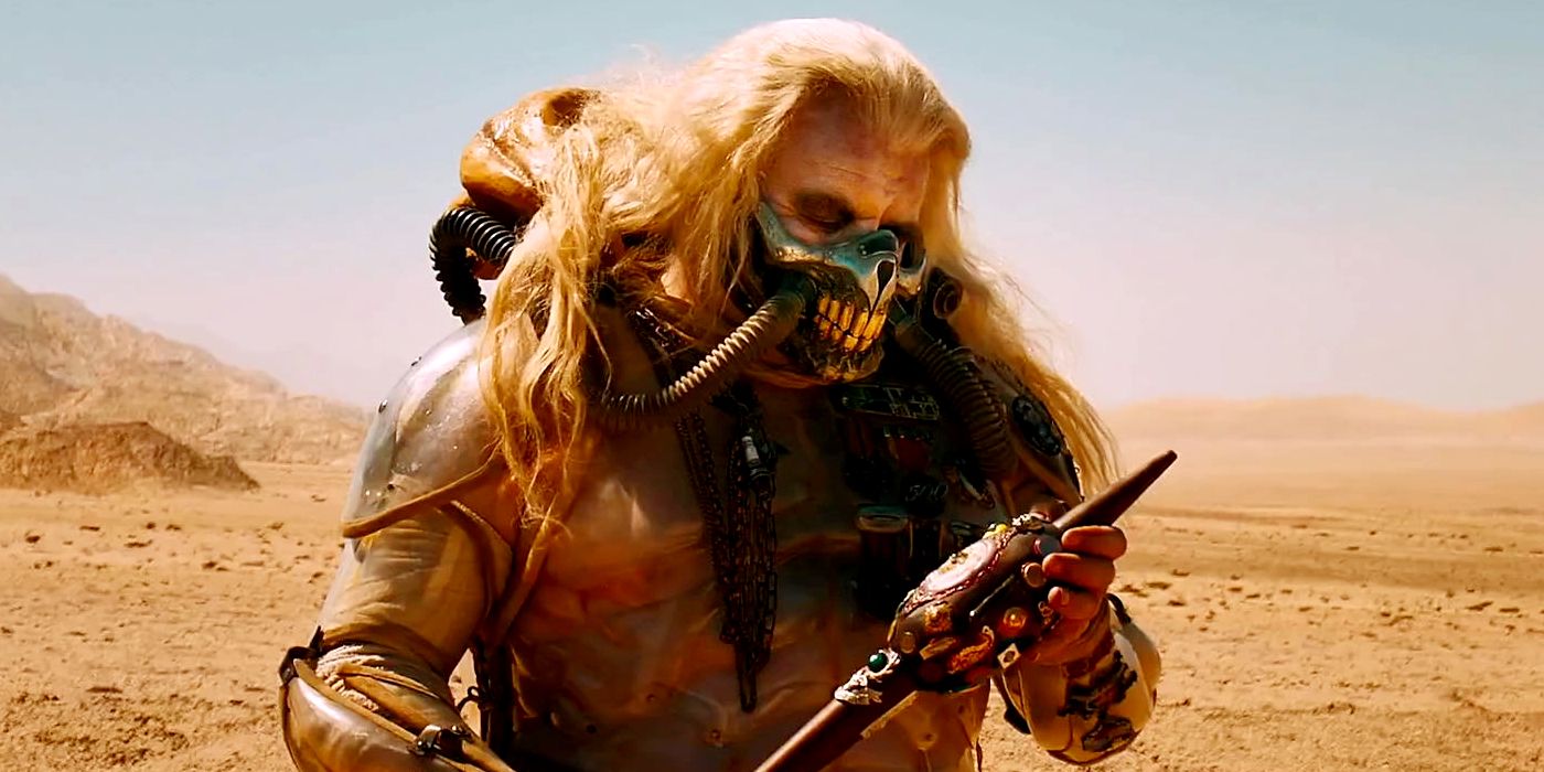 Immortan Joe holding something in his hands and examining it