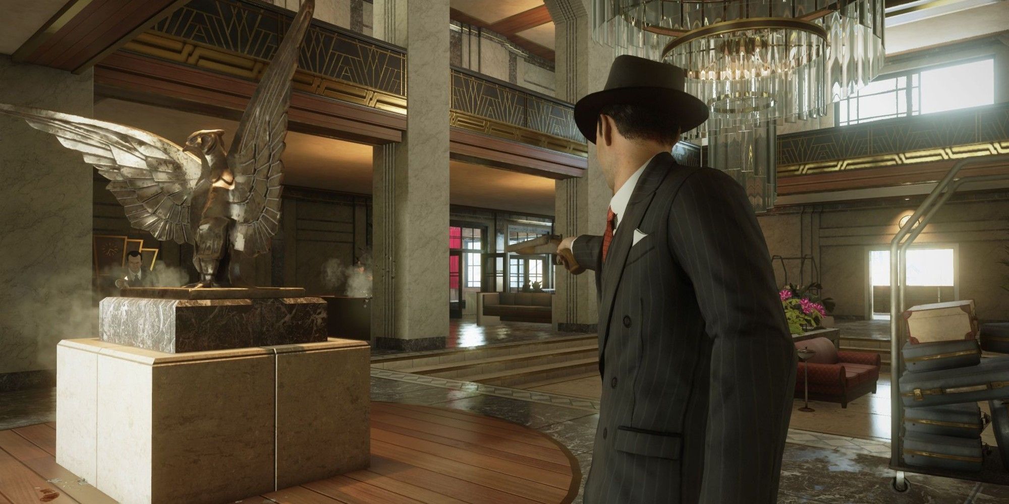 Tommy standing in a hotel lobby pointing a pistol in Mafia: Definitive Edition.