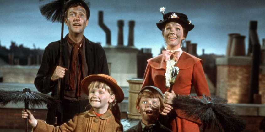 Mary Poppins (Julie Andrews) and Bert (Dick Van Dyke) standing and smiling with the Banks kids in Mary Poppins.