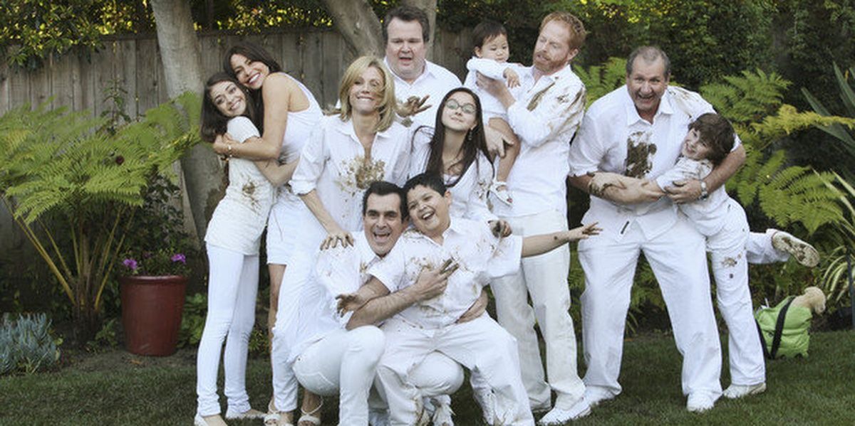 The entire Modern Family cast wearing white, with mud spattered on them 