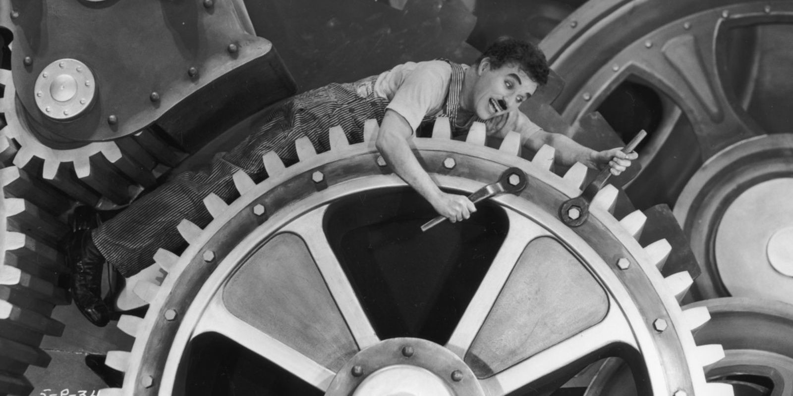Charlie Chaplin laying across the gears of a clock