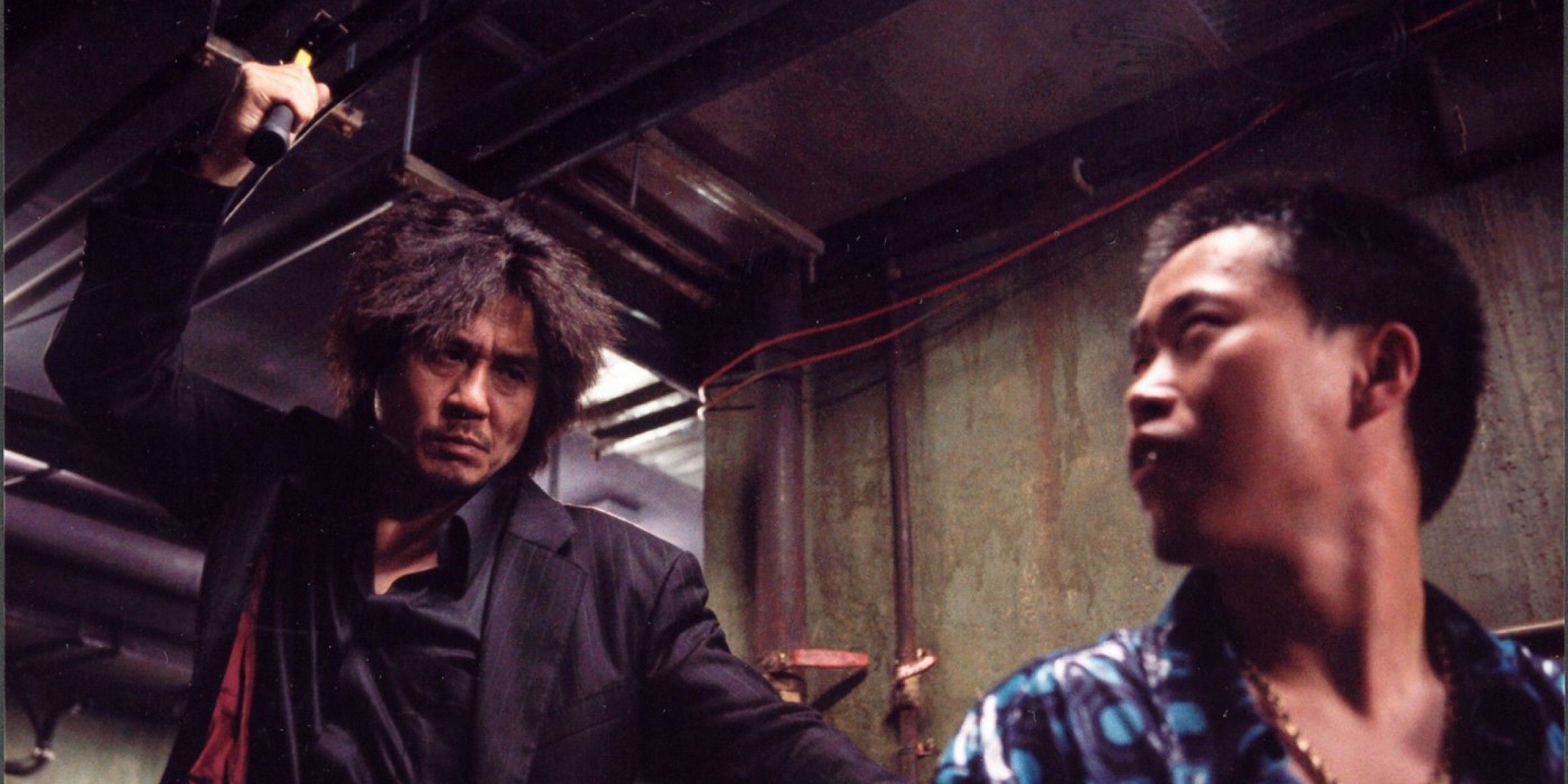 Dae-su raises his hammer to strike a young man in Oldboy.
