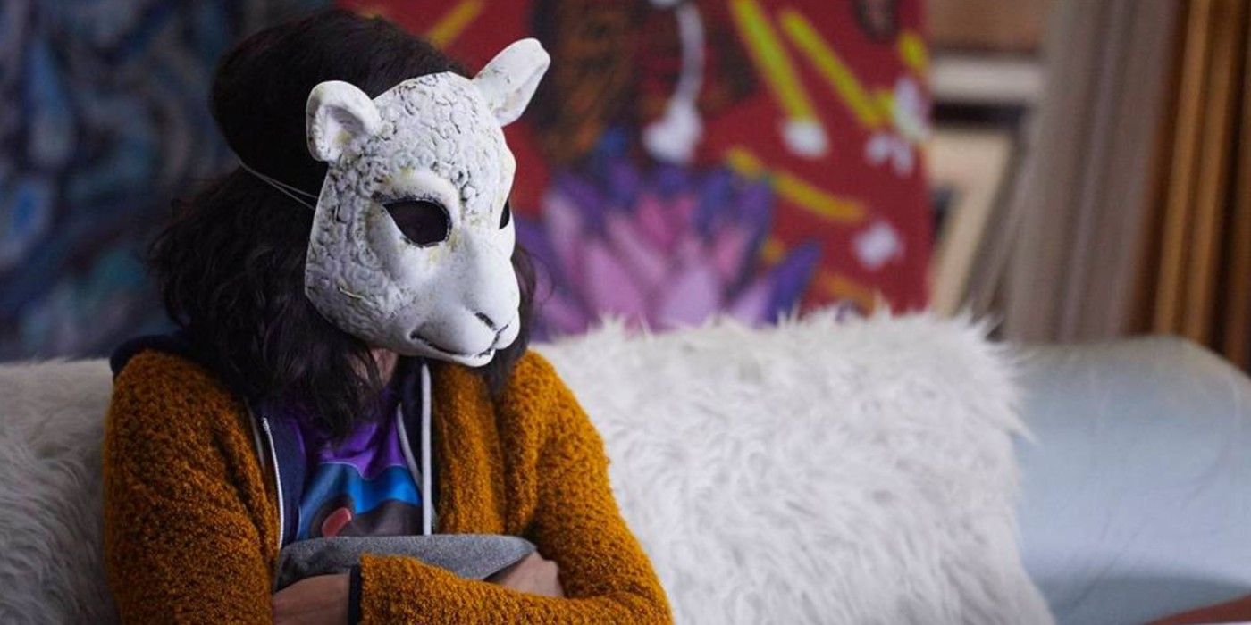 MK sitting on a couch, wearing her lamb mask in Orphan Black