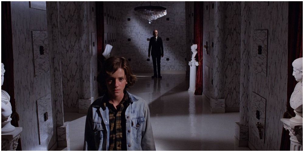 Woman Walking Down A Hall With Man Behind Her