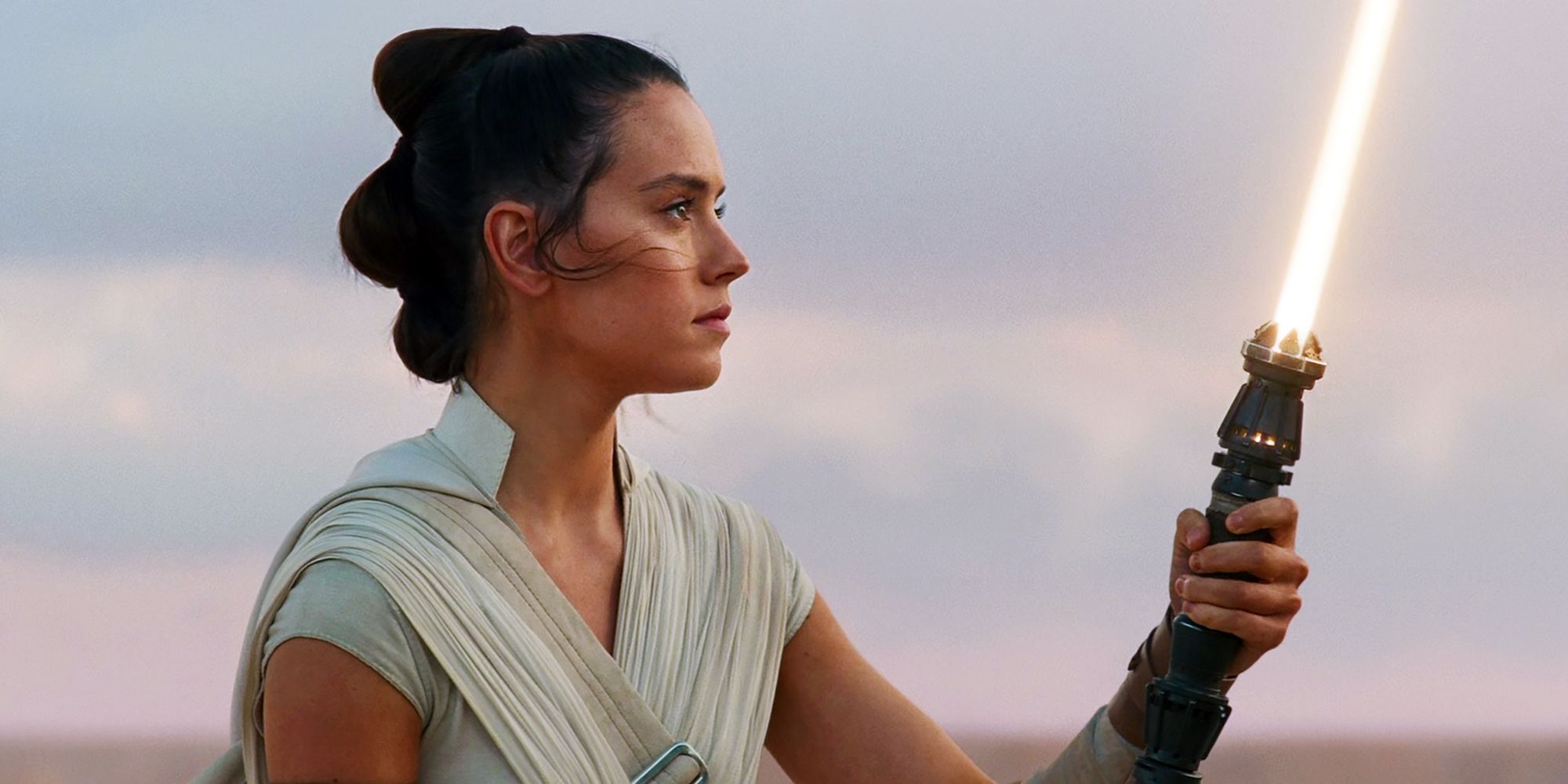 Rey holds her new yellow Lightsaber in Star Wars: The Rise of Skywalker.