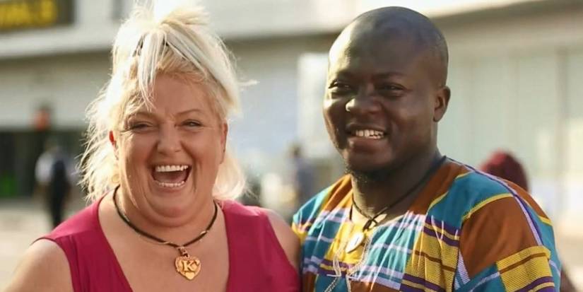 Michael in printed shirt and Angela Deem in red top from TLC: 90 Day Fiancé posing in Nigeria smiling.