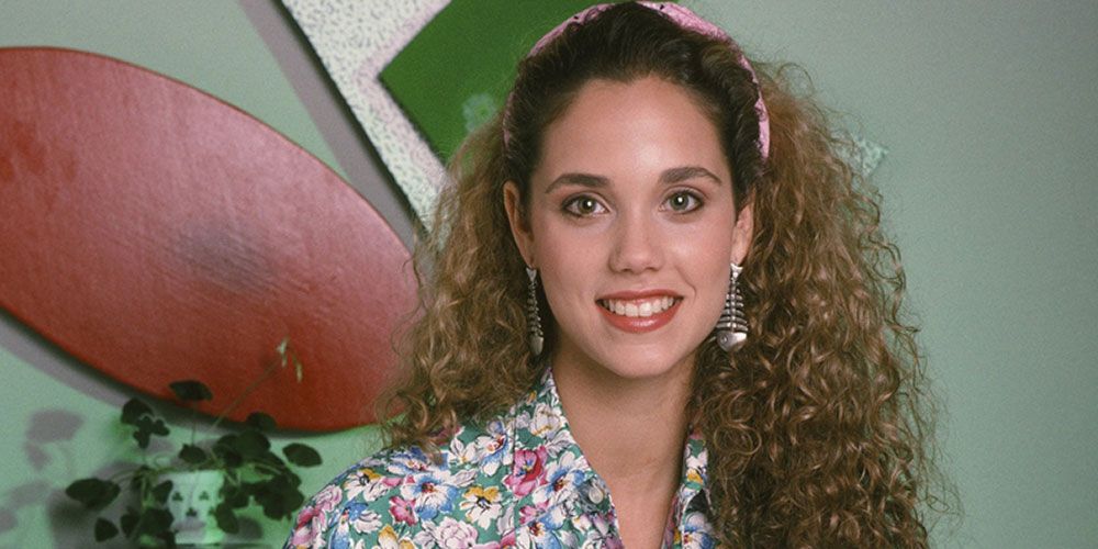 Jessie smiles in front of geometric shapes on the wall at The Max set on Saved By The Bell