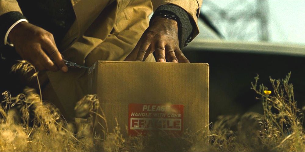 Morgan Freeman bending down and touching a mysterious box in Se7en (1995)