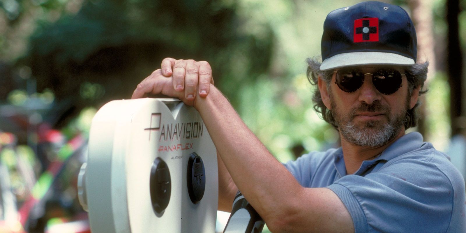 Steven Spielberg on the set of Jurassic Park with his hands on a camera.