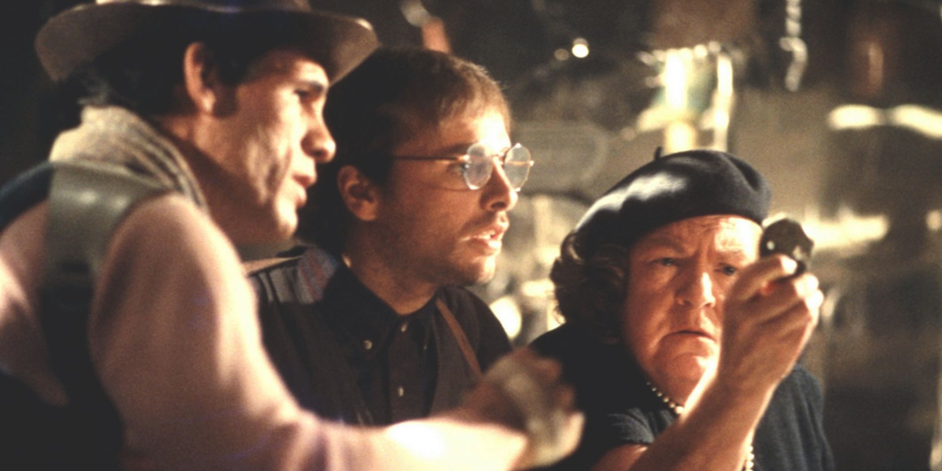 Anne Ramsey as Mama Fratelli, Robert Davi as Jake Fratelli, and Joe Pantoliano as Francis Fratelli looking at treasure in The Goonies.