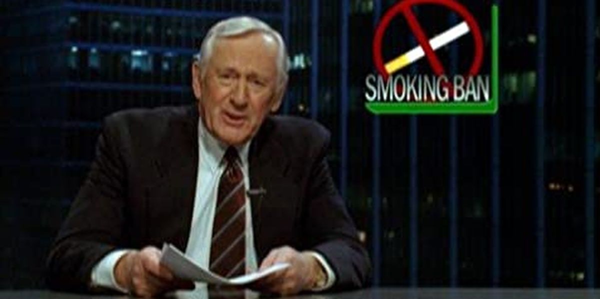 Len Cariou in The Onion Movie sitting at a desk holding some papers