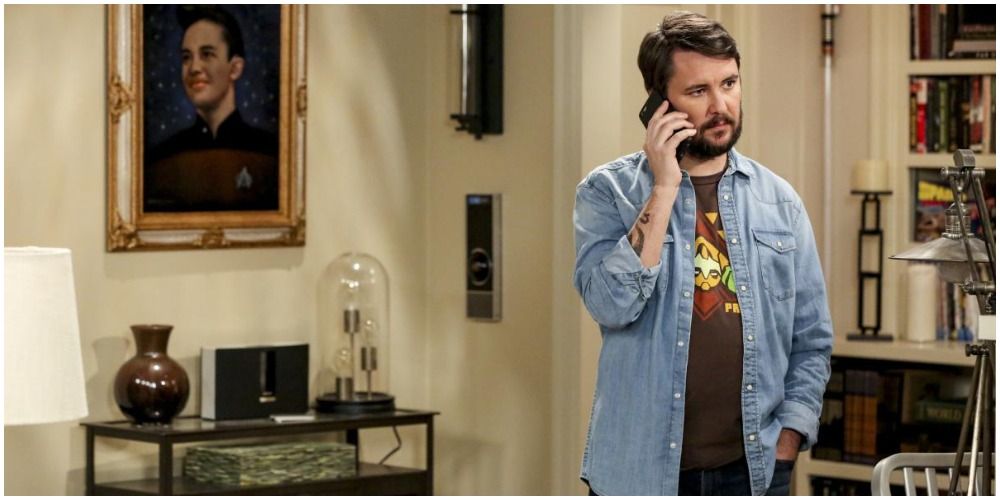 Will Wheaton in a blue denim shirt and tee talking on the phone on Big Bang Theory