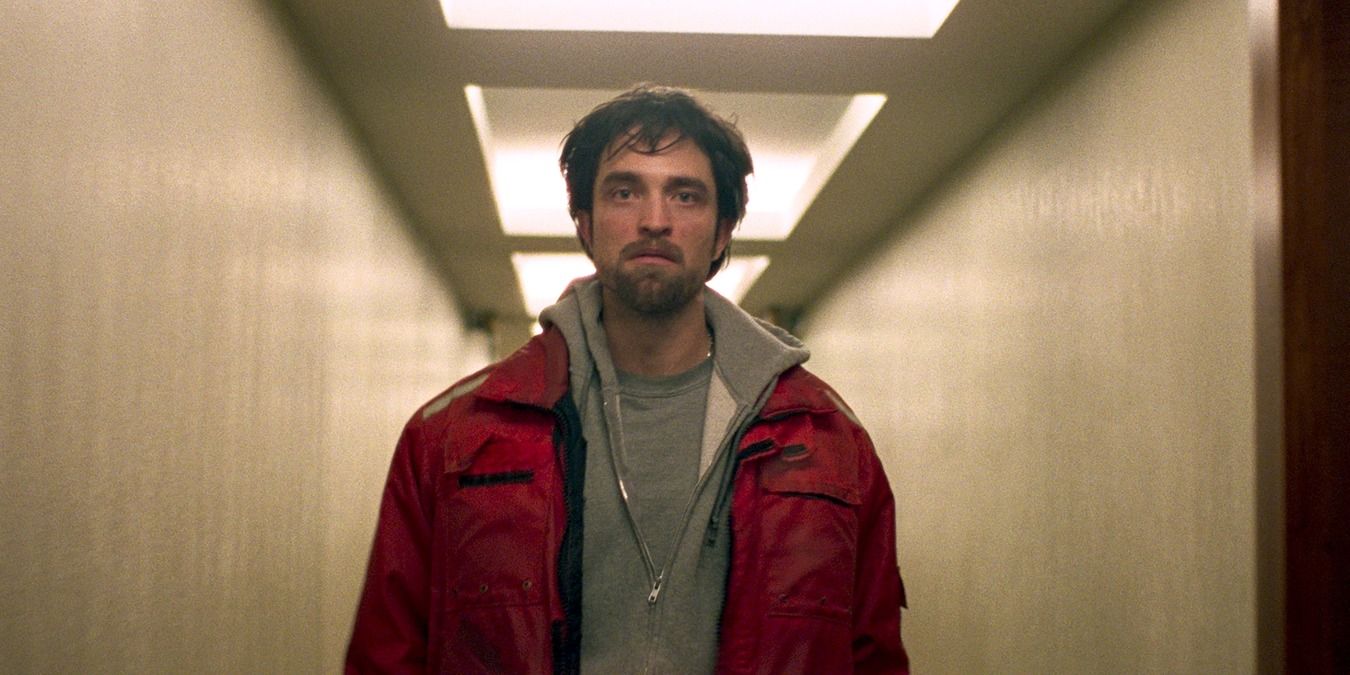 Robert Pattinson walks down a hallway in Good Time