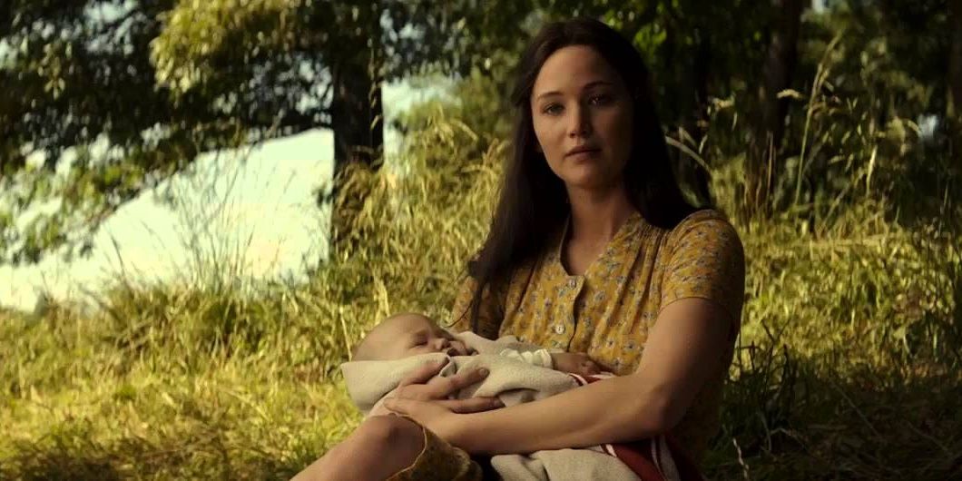 Katniss segurando seu bebê e sorrindo suavemente em Jogos Vorazes A Esperança Parte 2.