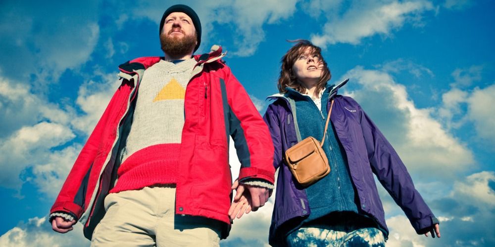 Chris and Tina in front of the sky wearing colorful anoraks in Sightseers