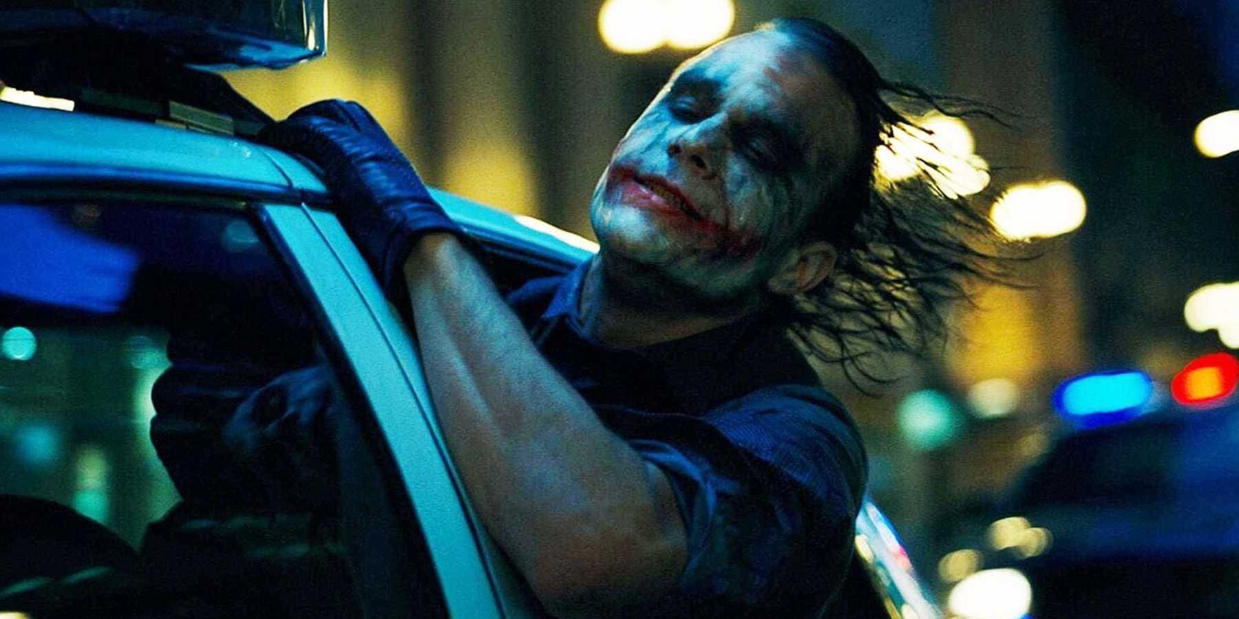 Heath Ledger as The Joker leaning out of a car window.
