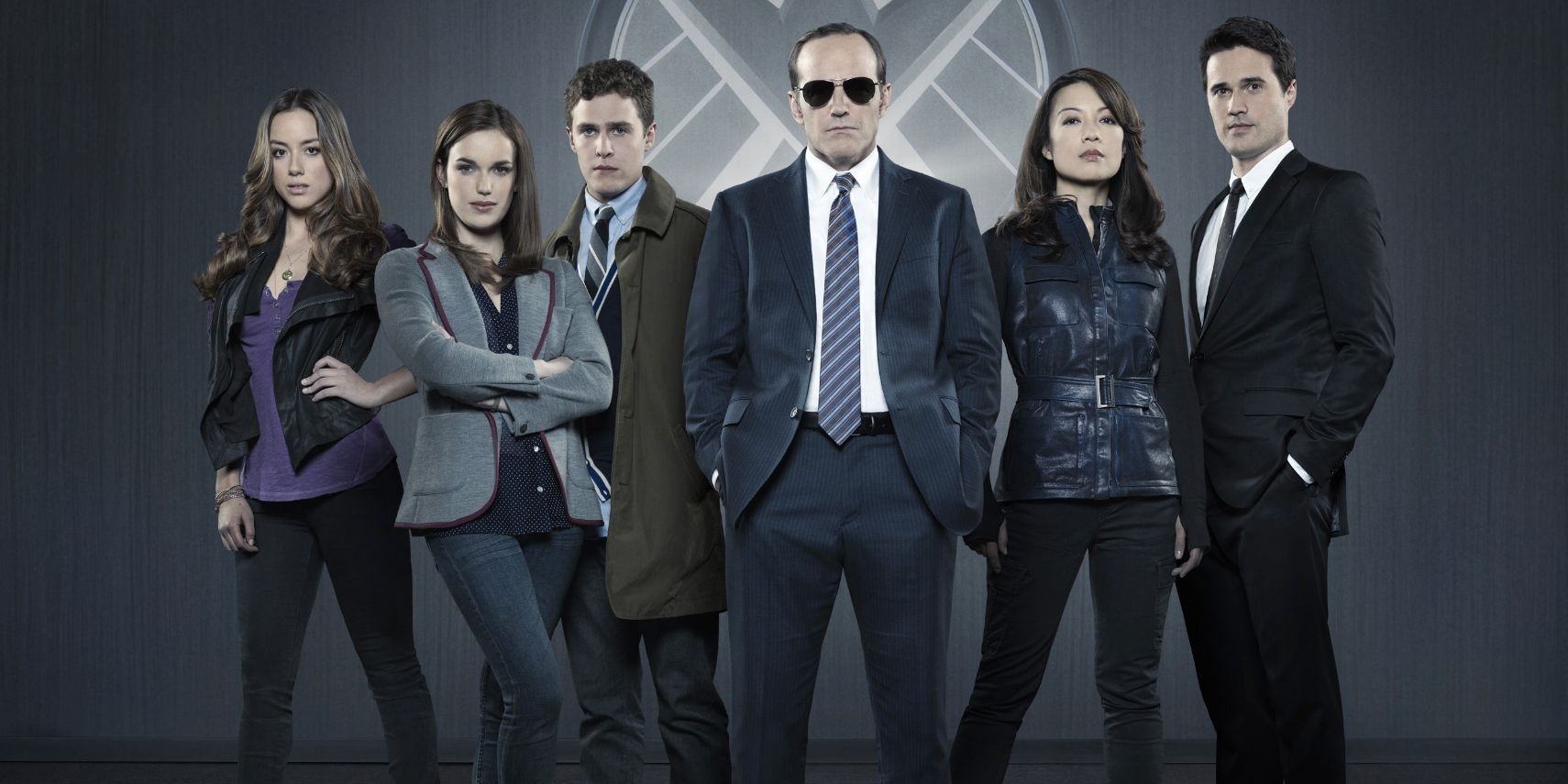 The cast of Marvel's Agents of S.H.I.E.L.D. poses in front of a logo