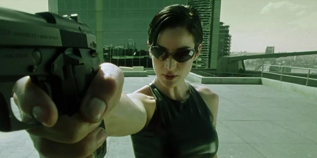Carrie-Anne Moss as Trinity holding a gun in The Matrix