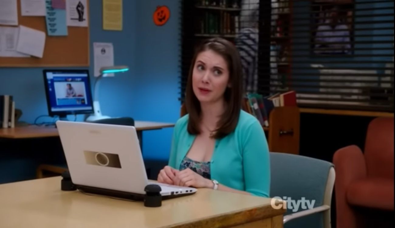 Beetlejuice walks behind as Annie sits in front of a laptop