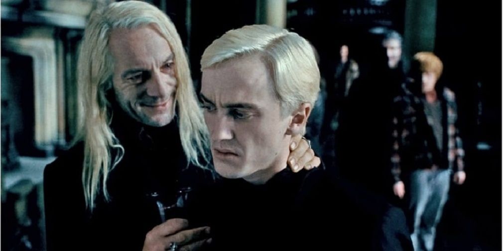 Draco and Lucius Malfoy talk with Ron behind them