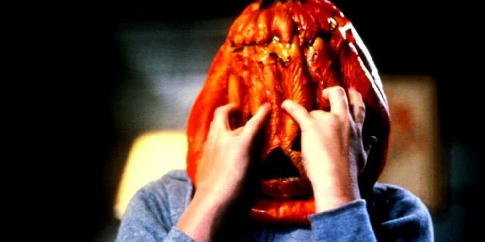 A young man puts a pumpkin on his face in Halloween 3