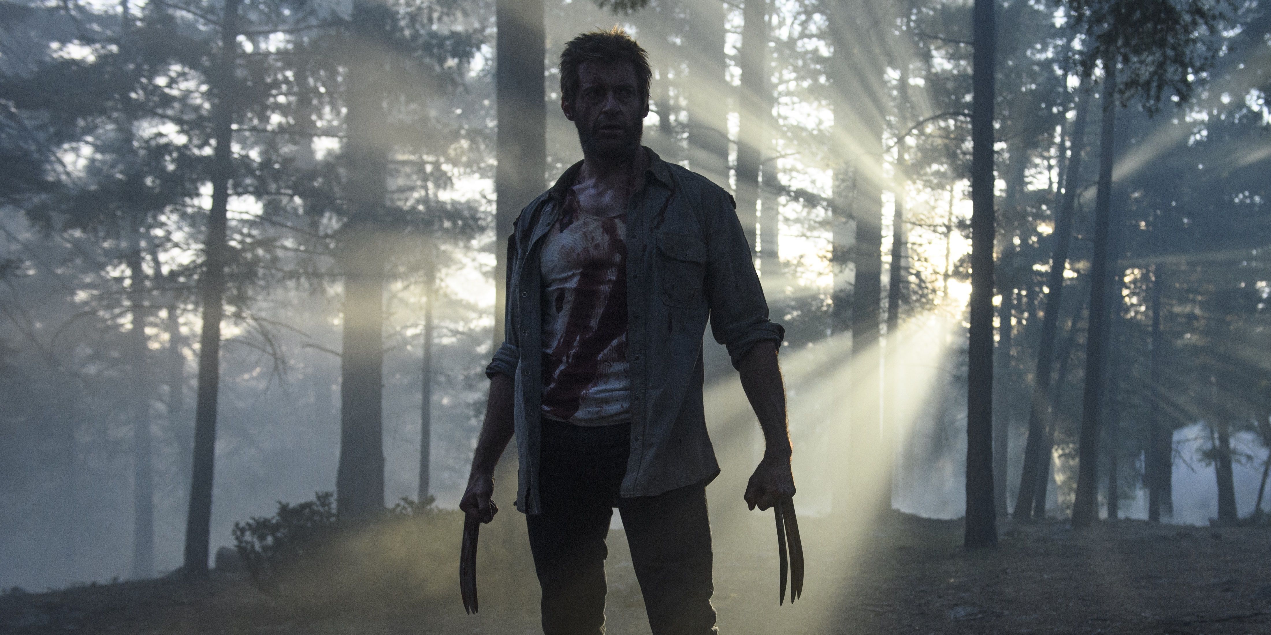 Hugh Jackman as Wolverine standing in a forest in Logan.