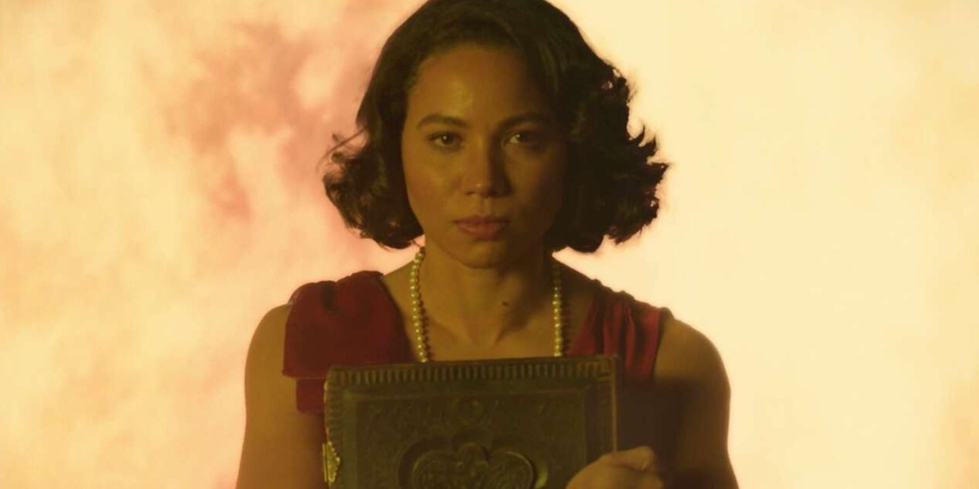 Jurnee Smollett in Lovecraft Country con libri e fiamme sullo sfondo
