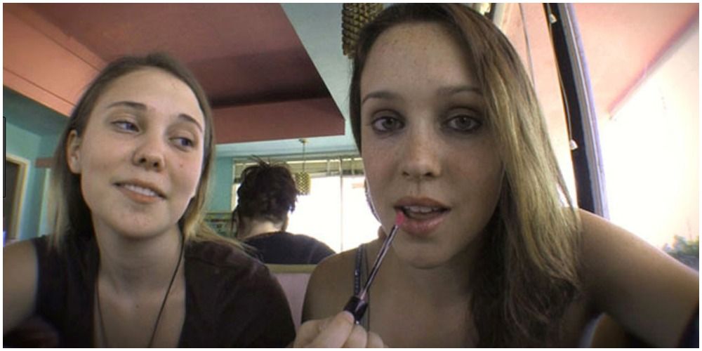 Girls Taking A Picture On A Phone And Putting On Lipgloss