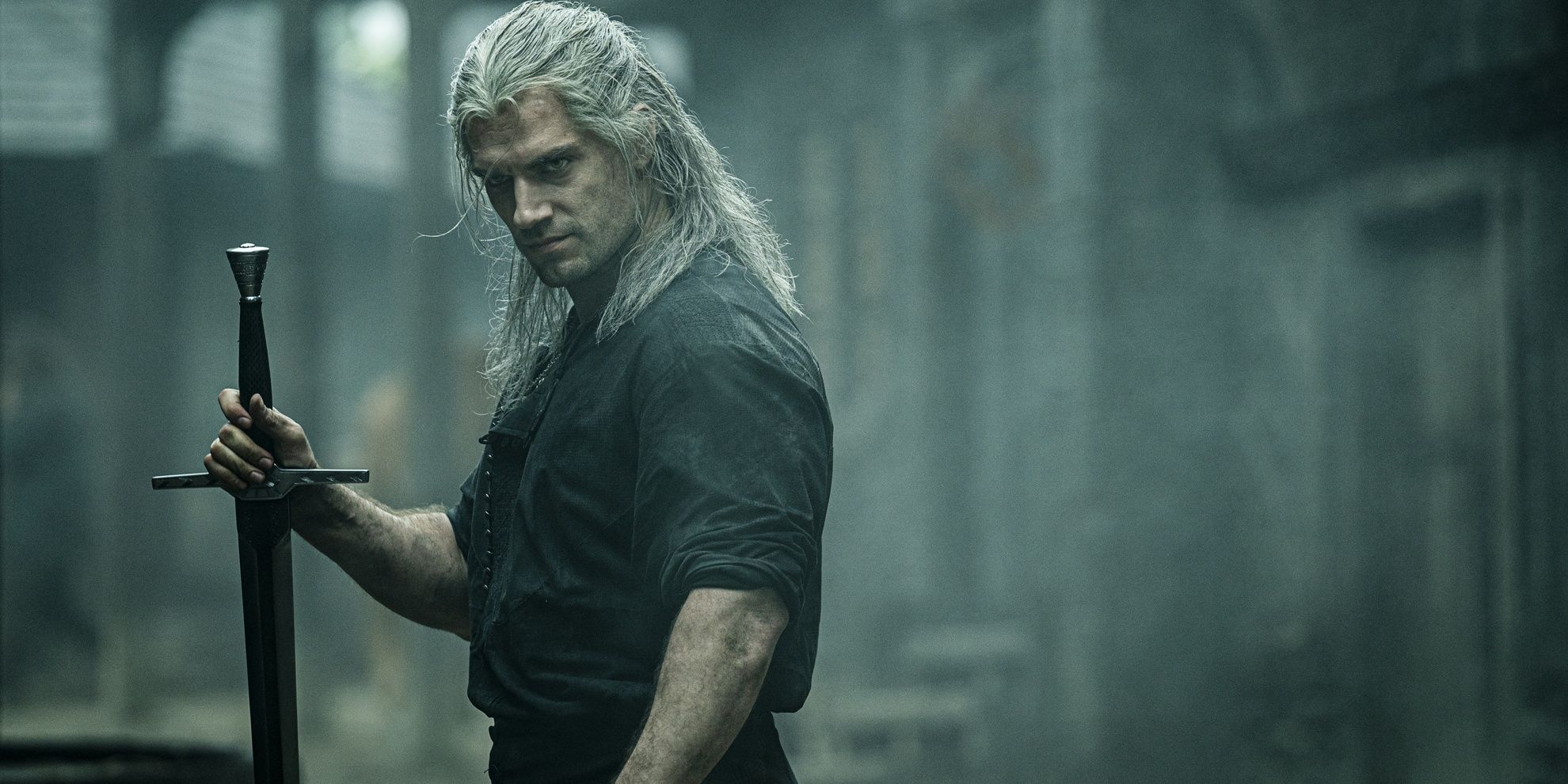 Geralt of Rivia (Henry Cavill) holding a sword in The Witcher