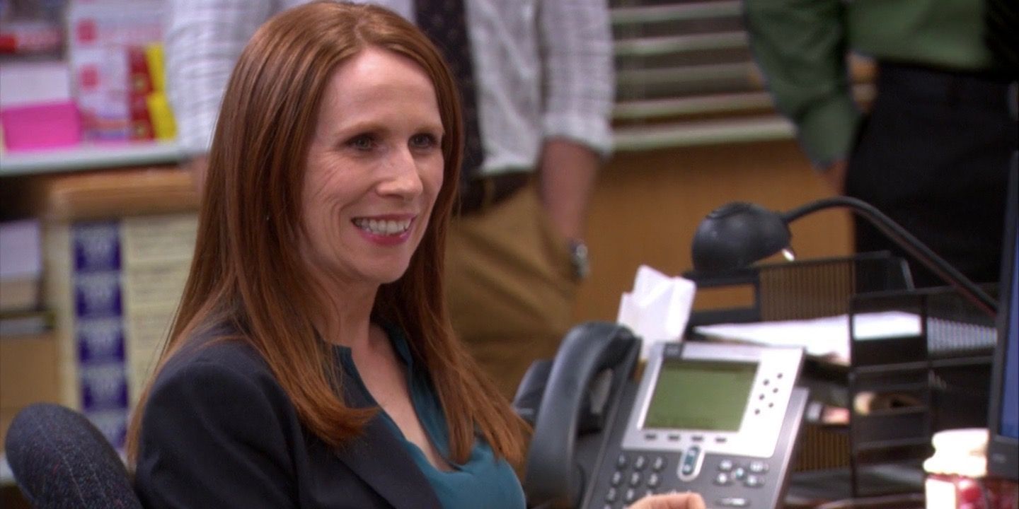Nellie smiling while sitting at Scranton desk in The Office