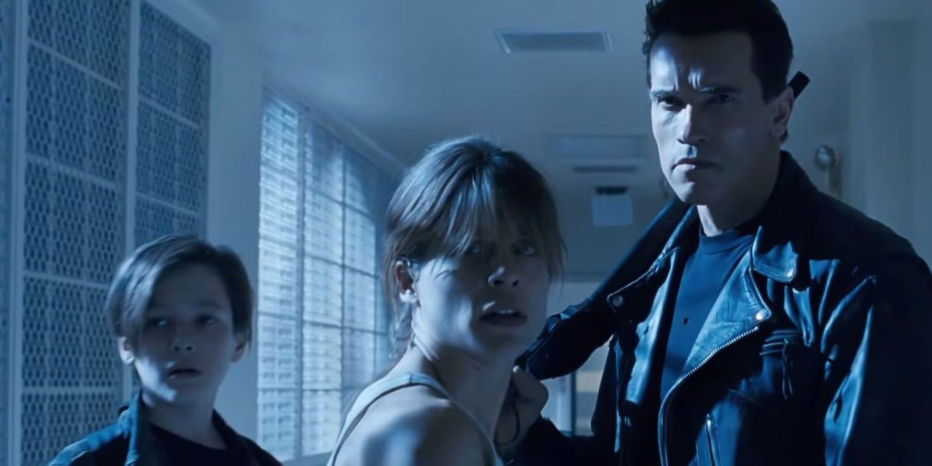 Sarah, John, and the T-800 look worried in a hallway in Terminator 2