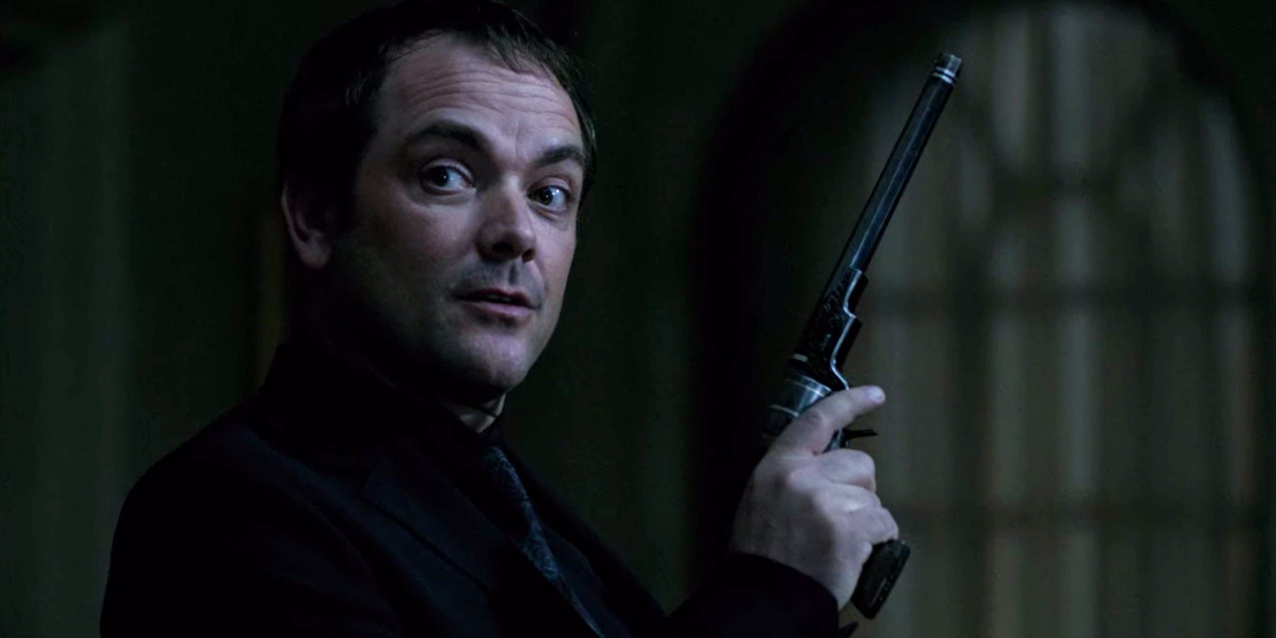 Crowley smirking holding the Colt
