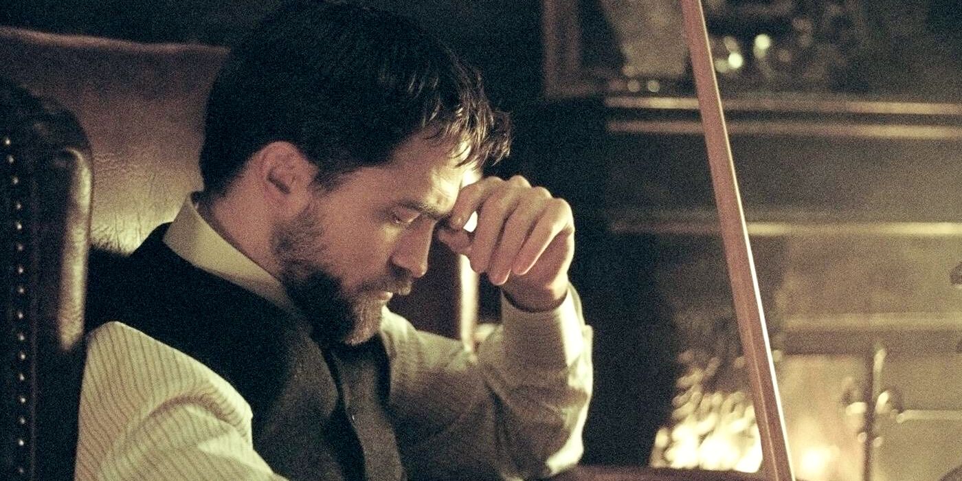 Robert Pattinson looking serious sitting in an armchair in Childhood Of A Leader 