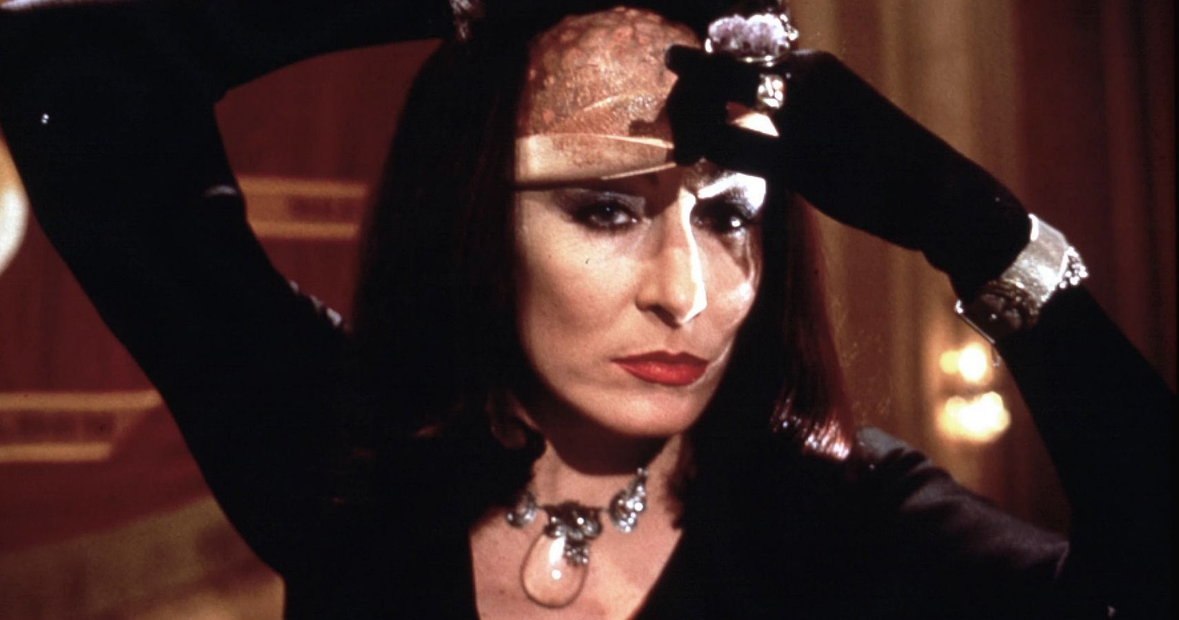 A profile shot of the Grand High Witch taking off her disguise in The Witches (1990)