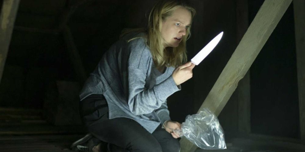 Elisabeth Moss as Cecilia in The Invisible Man 2020 holding a knife in the attic