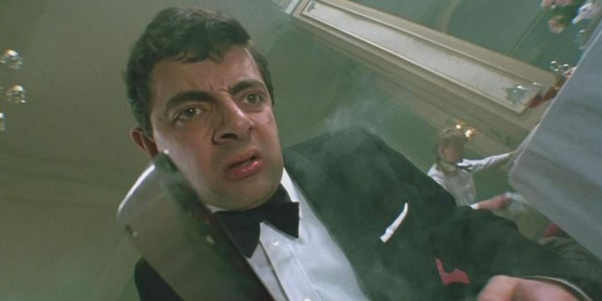 A screenshot of Rowan Atkinson's Mr. Stringer about to strike the Grand High Witch as a mouse with a butcher's knife in The Witches (1990)