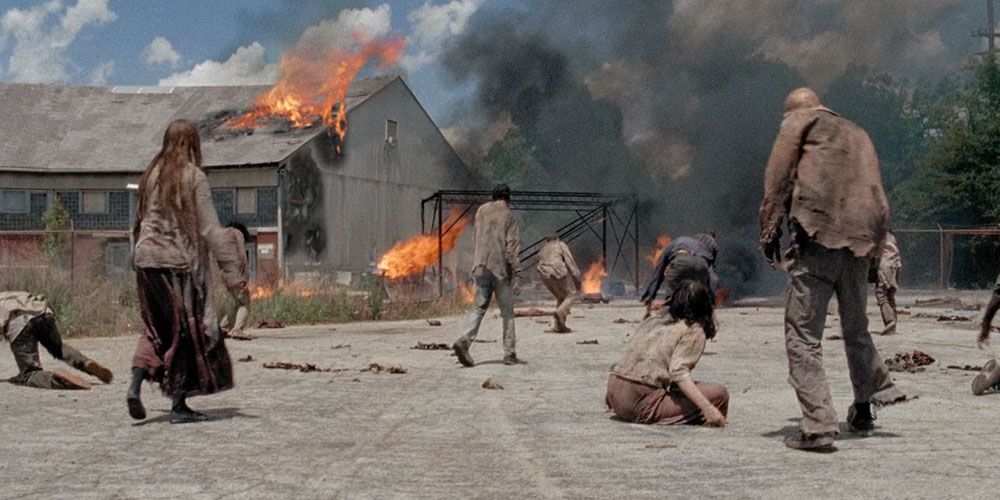 Walkers walk towards the flaming buildings of Terminus in The Walking Dead