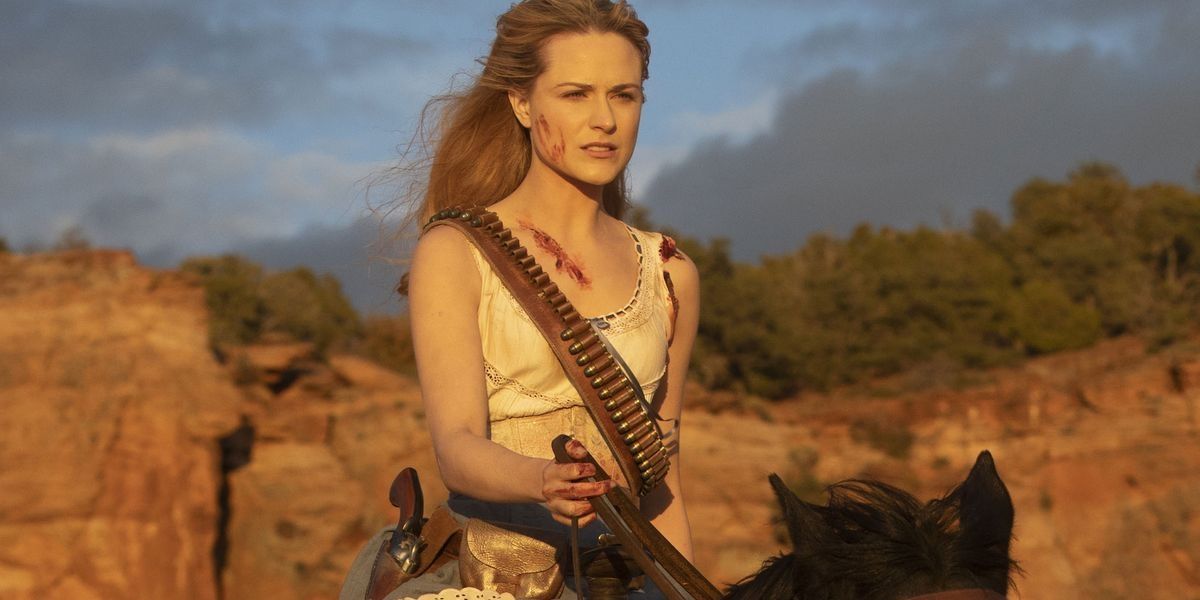 A bloodied Dolores holding her gun and riding a horse in Westworld