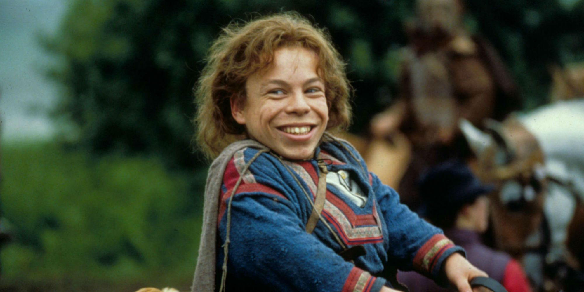Warwick Davis smiling while riding a horse in Willow