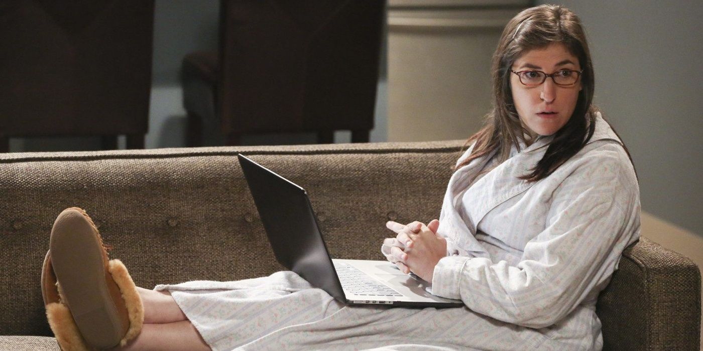 Amy Farrah Fowler in her pajamas with a laptop on her lap in The Big Bang Theory