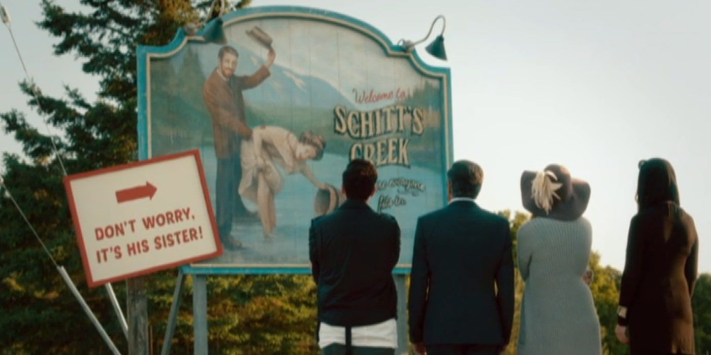 Rose family looking at Schitt's Creek town sign