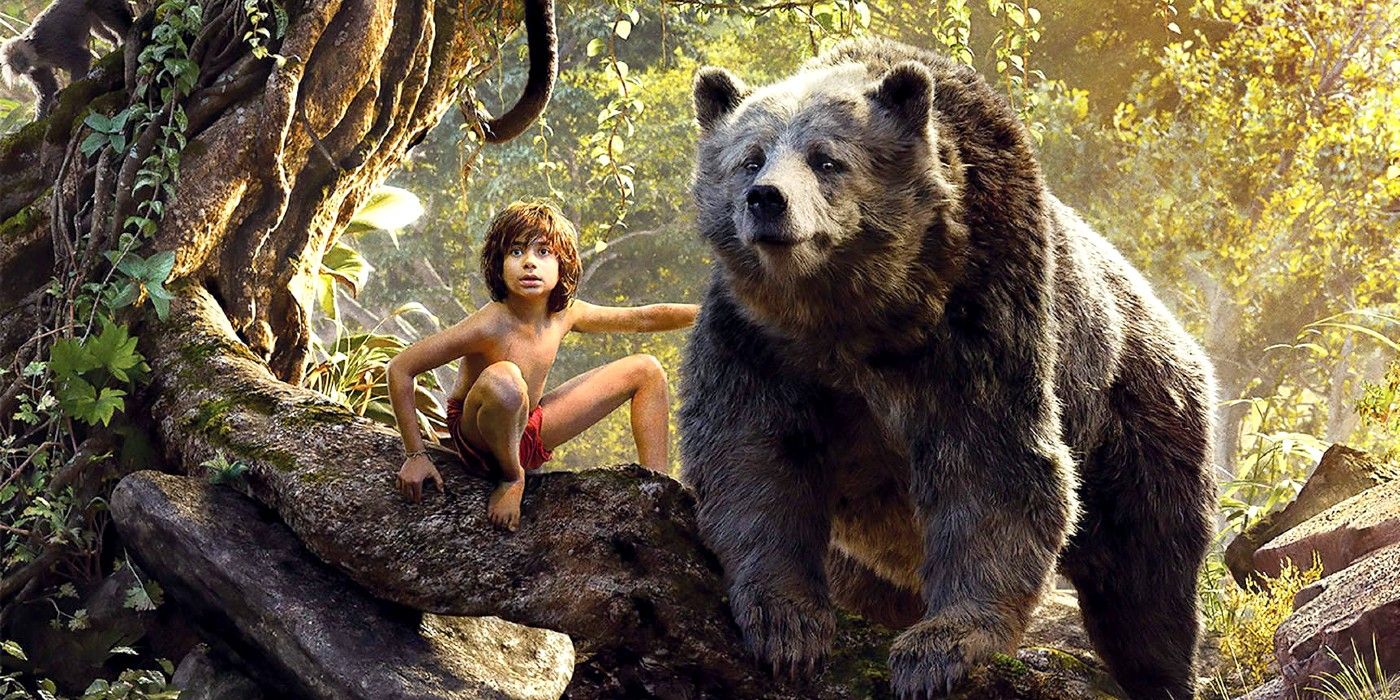 Mowgli and Baloo perch on a tree branch in the Disney live-action The Jungle Book.